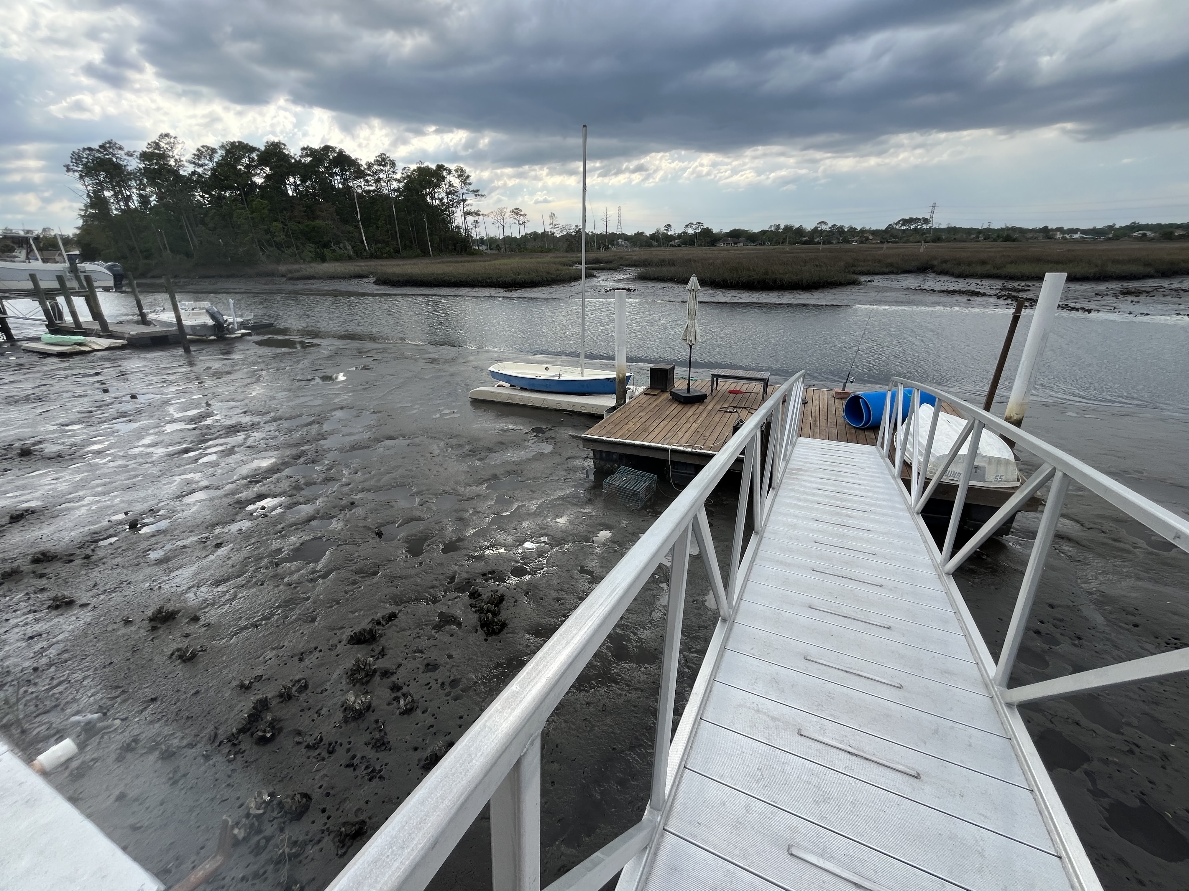 Dock and boats stranded on mudflats at low tide in Hogpen Creek
